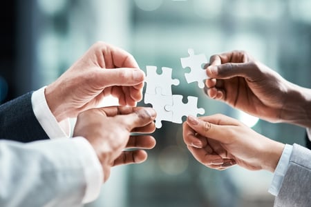 four hands put together puzzle pieces