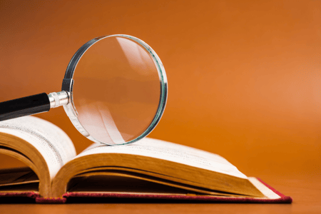 magnifying glass on top of book with orange background