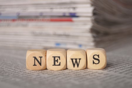 blocks that say 'news' with newspapers in the background