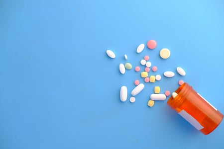 blue background with pill container and multi colored pills coming out